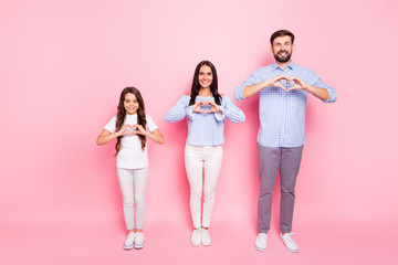 Naklejka premium Pełnowymiarowe zdjęcie pozytywnej mamy, taty i dziewczynki noszących białą koszulkę w kratkę koszula w kratę, które sprawiają, że serce z palcami odizolowanymi na różowym tle