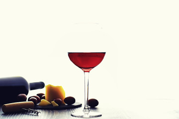 A glass of red dry wine on the table. Dark bottle and glass of wine.
