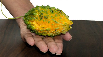 Green and yellow bitter gourd in hand with wood chopping board isolated