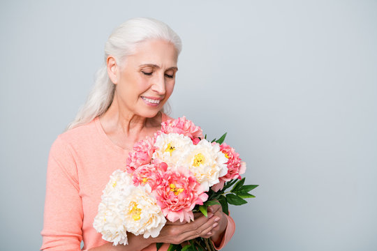 Close up photo of gorgeous lady holding large bouquet of beautiful flowers in hands isolated grey background