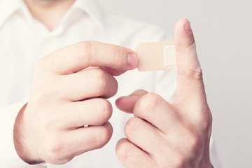 Men's hands, stick plaster on finger, cropped image, close up, toned