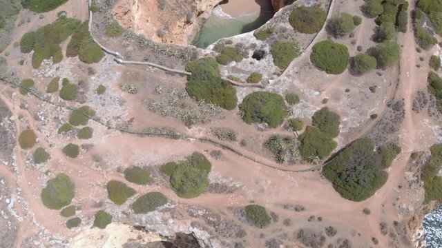 Drone fly over Algarve cliff coastline. Aerial Zoom out of  Hidden caves in Carvoeiro near Praia Dos tres castelo and Arriba de Salgadeira viewpoint.