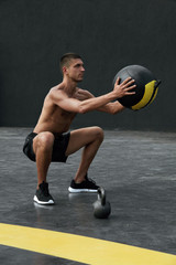 Exercise. Sport man doing squat workout with med ball at gym