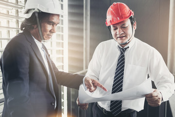 Contractor and engineer with blueprints discuss at a modern construction site, Engineers in...
