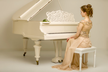 The girl is at the white grand piano.