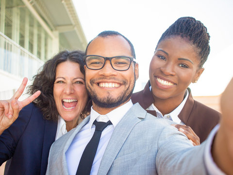 Joyful multiethnic business people taking group selfie. Self portrait of happy business man and women showing peace gesture. Multiethnic team concept
