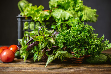 Fototapeta premium Box with fresh vegetables and green salad on a dark background. Organic raw products grown on the farm.