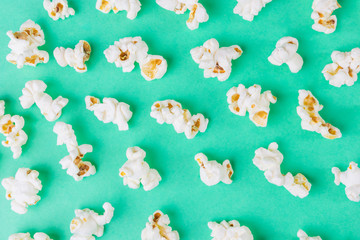 Popcorn close-up on a green background. Unhealthy diet concept. Minimalism, flat lay, top view, place for text.