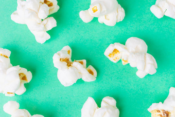 Popcorn close-up on a green background. Unhealthy diet concept. Minimalism, flat lay, top view, place for text.