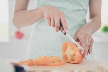 Cropped photo of mother slicing pepper to add it into salad she will cook for children and husband hating pepper