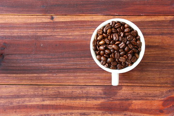 Obraz na płótnie Canvas topview,flatlay coffee beans in white cup on brown retro wood,copyspace