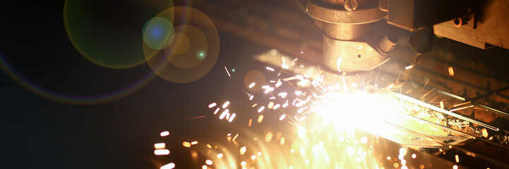 Industrial laser machine for metal cutting. Orange sparkles blurred background