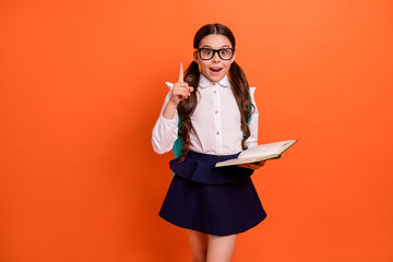 Portrait of nice impressed kid hold hand printed book lesson material wear white tails stylish trendy blouse shirt dress eyewear eyeglasses bag backpack rucksack isolated orange background