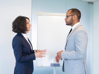 Excited intern consulting trainer in conference room. Male and female business colleagues standing...