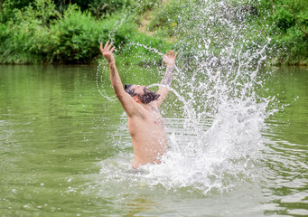 Splashes of freedom. Man enjoy swimming in river or lake. Submerge into water. Freshness of wild nature. Summer vacation. Deep dangerous water. Relaxation and rest. Swimming sport. Swimming skills
