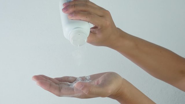 Close-up hand of woman pouring talcum powder onto the palm, isolated on white background.
