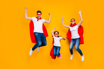 Fototapeta na wymiar Crazy daddy mommy and foxy daughter jumping high wear cartoon superhero capes isolated yellow background