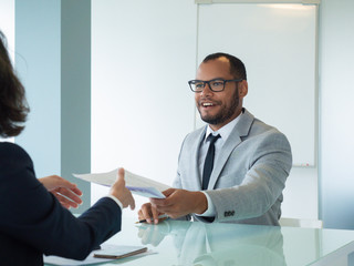 Business partners closing agreement. Businessman giving documents to female partner after signing....
