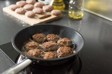 Cutlet from minced meat is cooking in frying pan.