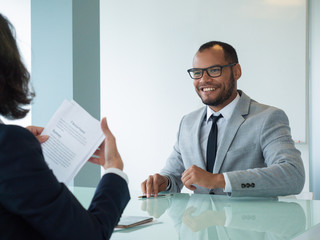 Happy businessman satisfied with deal. His female business partner sitting opposite of him and...
