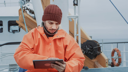 Dressed in Protective Coat Fisherman Using Tablet Computer with Navigation Maps while Traveling on...