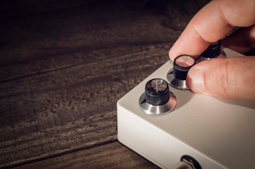 Hand sets the controls on an electric guitar pedal
