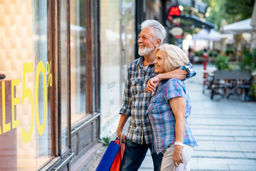 Happy senior couple in shopping looking at window