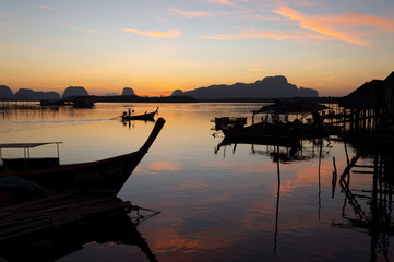 Fishermen village at sunrise..Silhouette landscape of fishermen pier and boats when the sun is...