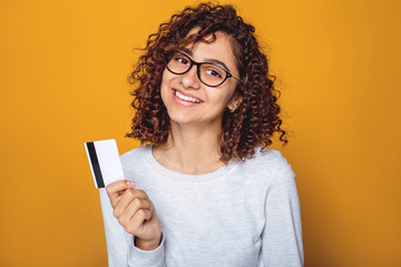 Portrait of a smiling Indian young woman holding a credit card in her hand. 
