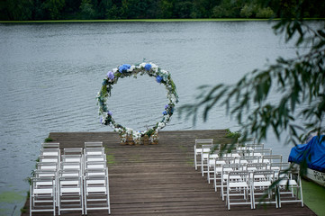 Round arch with white and blue flowers. Check-out on the river or lake. Wedding registration.
