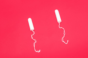 Two tampons on a red background, close up, copy space, top view, menstrual period concept