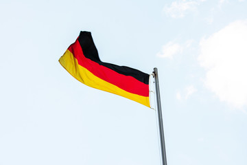 German flag, waving flag of Germany, close up, blue sky