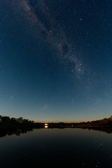 As the sun sets the milky way galaxy appears above a dam in Storm King, Queensland, Australia