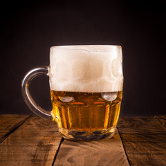 Very cold beer jug on a wooden table on a black background. Concept for the oktoberfest party.