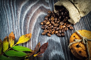 Autumn leaves, coffee grains and cookies on wooden background