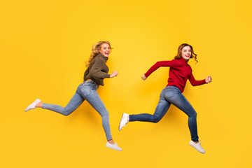 Full size photo of funny ladies jumping high hurrying shopping wear knitted sweaters isolated yellow background