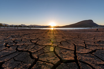 The sun sets setting over a lake it shows the dry cracks in lake bed. On a clear and sunny day in Lake Moogerah, Queensland, Australia