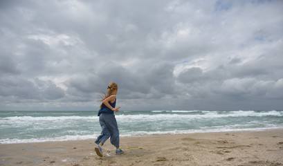 Fototapeta na wymiar girl running on the sandy beach by the sea