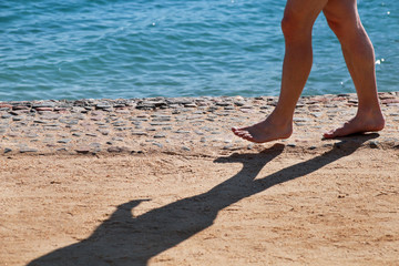 Man legs on sand. Male feet walking on beautiful sandy beach of hotel resort on Red sea in Egypt, doing and leave behind footprints in sand. Man on vacation in summertime. Travel and holiday concept.