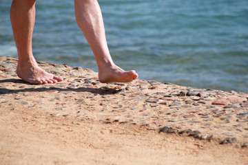 Man legs on sand. Male feet walking on beautiful sandy beach of hotel resort on Red sea in Egypt, doing and leave behind footprints in sand. Man on vacation in summertime. Travel and holiday concept.