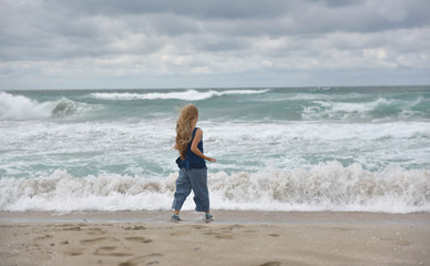 girl running on the sandy beach by the sea