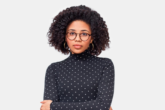 Image of pretty African American young woman, wearing casual outfit and eyewear. Afro female in black long sleeve shirt posing over white wall. People and emotions concept