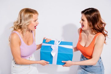 Photo of two ladies can't share one giftbox yelling each other wear casual clothes isolated white...