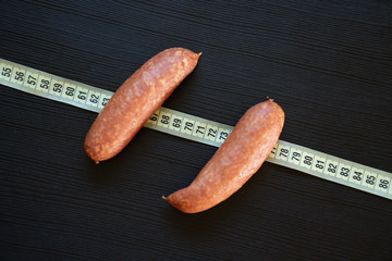 Diet concept - pork sausages wrapped with yellow measuring tape