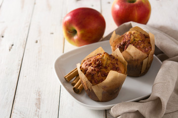 Apples and cinnamon muffins on white wooden table. Copyspace