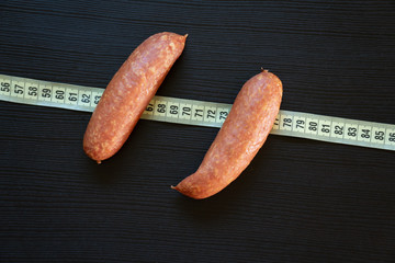 Diet concept - pork sausages wrapped with yellow measuring tape