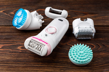 Epilator on dark wooden background.