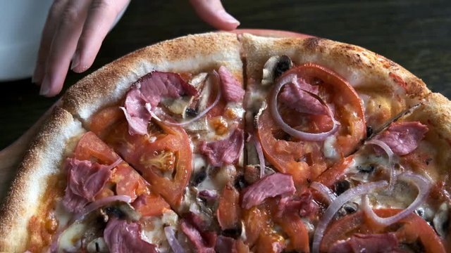 Top view of pizza with hands taking slices, slow motion