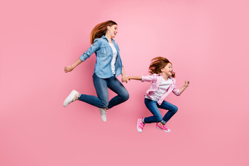 Fototapeta na wymiar Foxy small lady and her mom jumping high rushing toy shop wear casual jeans outfit isolated pink background