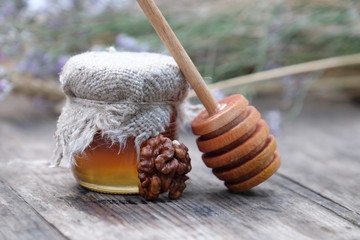 organic honey in jar, wooden honey dipper and nuts on natural background, healthy lifestyle,...